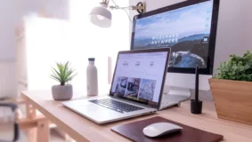 A laptiop and PC screen as a single workspace on a desk with a mouse.