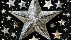 One large silver star surrounded by smaller silver stars on every side with a black background